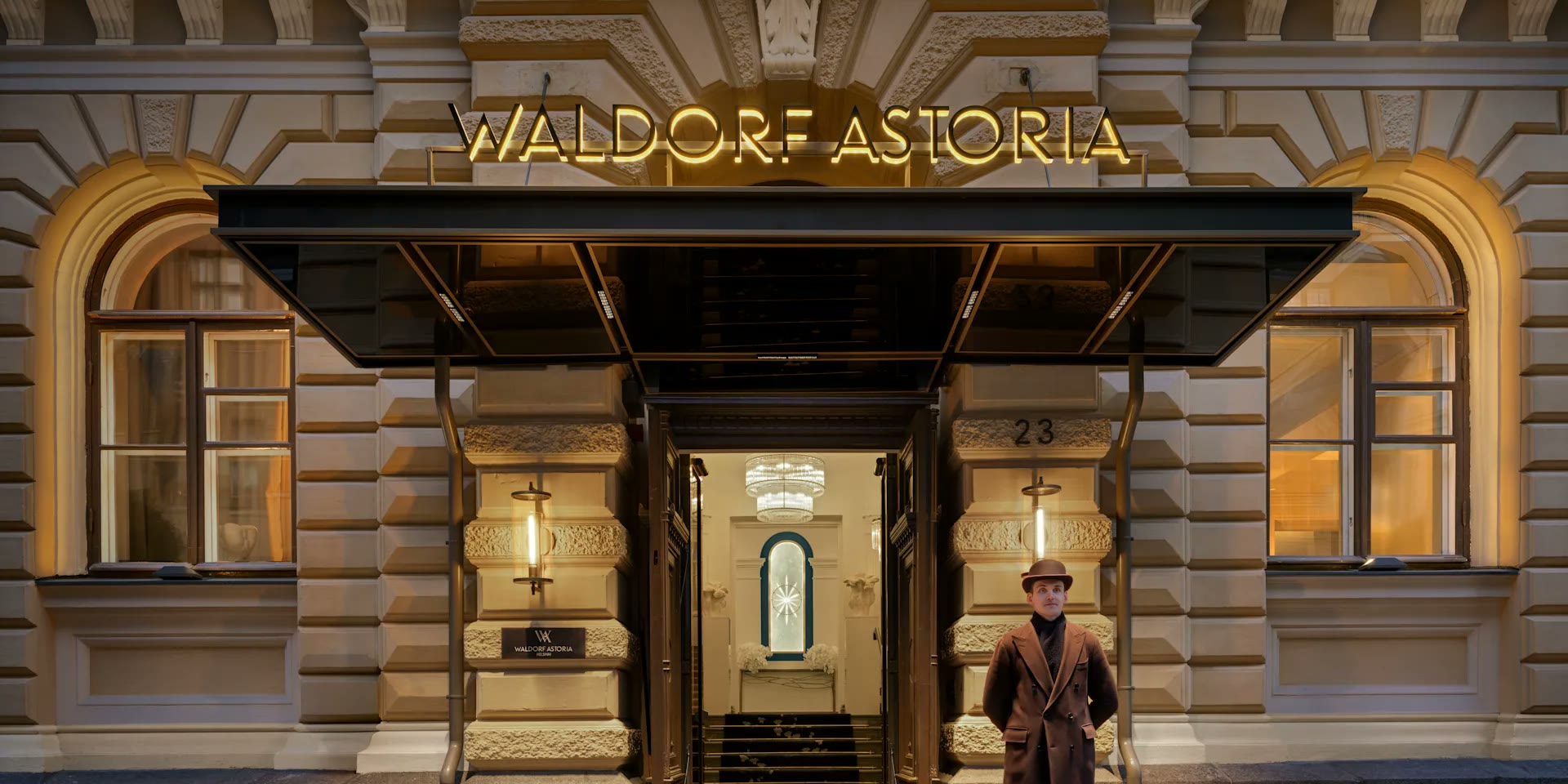 The Waldorf Astoria Helsinki entrance at dusk, doorman under the lit canopy